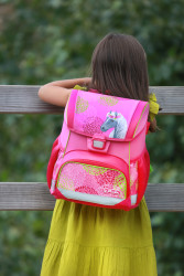 Schoolbag, girl looks over fen...