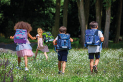 4 children with schoolbags run...